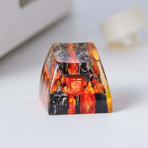 K&ouml;nnte beinhalten: Ein transparenter Harz-Tastenkappen mit einem roten und schwarzen Bild eines japanischen Tempeltors. Die Tastenkappe ist in Form einer traditionellen Tastaturtaste geformt.
