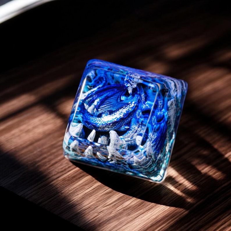 May include: A blue and white resin keycap with a detailed design of a dragon inside. The keycap is clear and shows the dragon in detail.