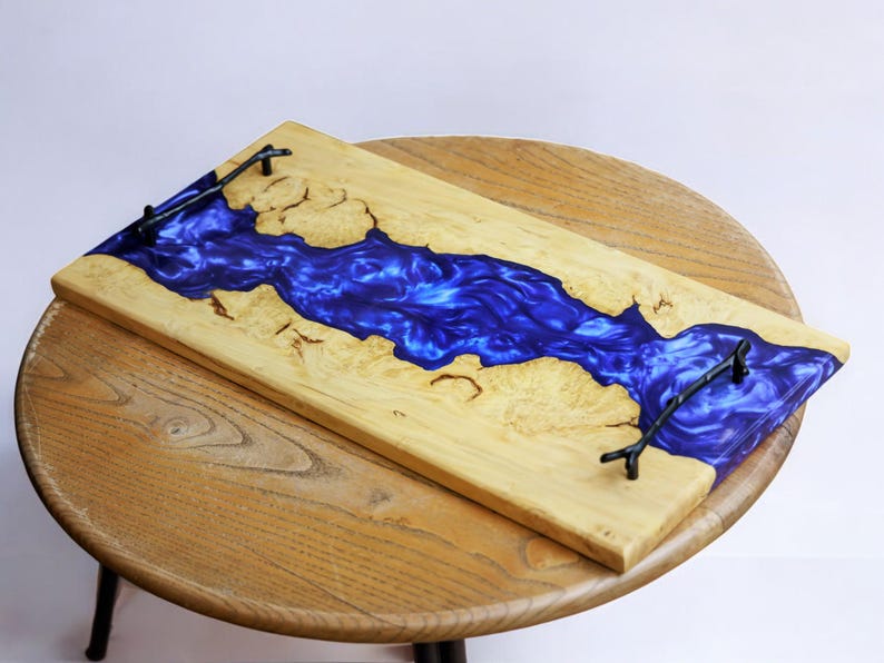 May include: A wooden serving tray with a blue resin inlay. The tray has two black metal handles.