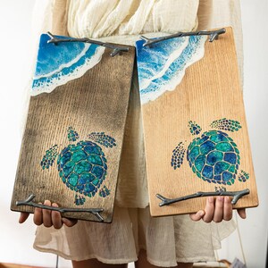 May include: Two wooden serving trays with resin ocean wave designs and a sea turtle graphic. The trays have rustic wood handles.