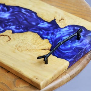 May include: A wooden serving tray with a blue resin inlay and a black metal handle. The resin has a swirling pattern.
