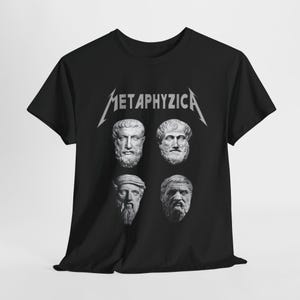 Puede incluir: Camiseta negra con un diseño plateado que presenta la palabra "METAPHYZICA" y cuatro bustos en escala de grises de figuras históricas. El diseño está centrado en la camiseta.
