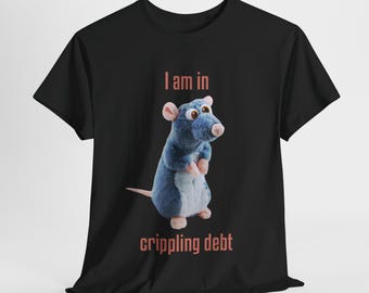 May include: Black t-shirt featuring a blue cartoon rat with large eyes. The text "I am in crippling debt" is printed above and below the rat. The shirt is made of a soft material.