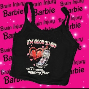 May include: Black tank top with the text "I'M GOOD TO GO" and a graphic of a broken heart and a flip phone. The phrase "and I'm going nowhere fast" is also printed on the tank top.