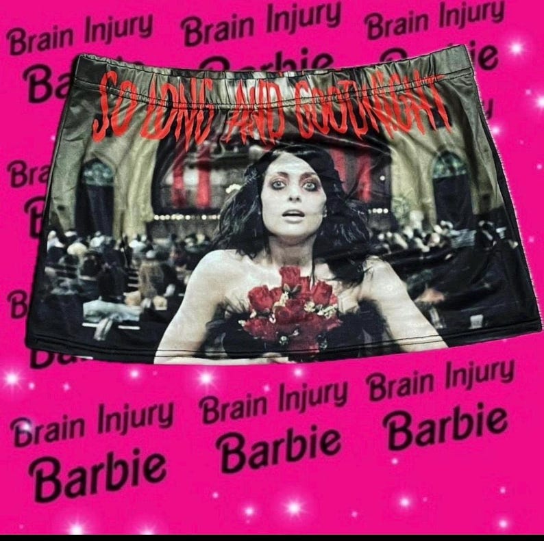 Pu&ograve; includere: Gonna mini nera con una stampa di una donna che tiene un mazzo di rose rosse. La gonna ha la scritta "So Divine and Goodnight" stampata su di essa.