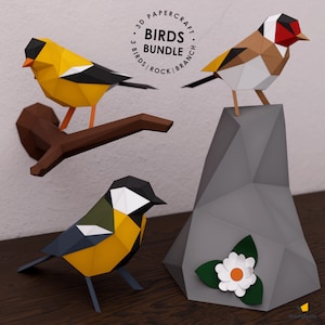May include: 3D papercraft model kit of three birds: a yellow and black bird on a branch, a red-headed bird on a gray rock, and a black, white, and yellow bird. The kit includes instructions for assembling the birds and a rock with a flower.