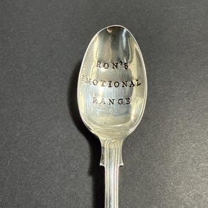 May include: A silver spoon with the words "Ron's Emotional Range" engraved on the bowl.