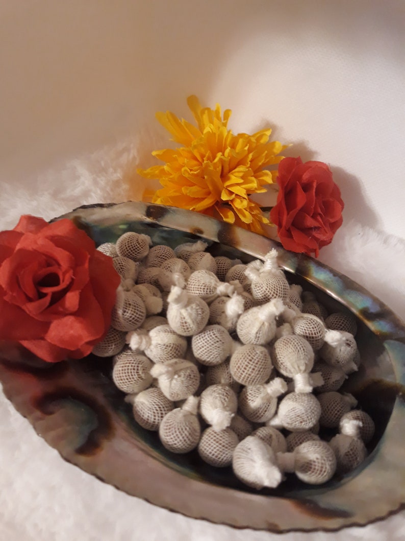 K&ouml;nnte beinhalten: Nahaufnahme einer Muschelschale, die mit kleinen, wei&szlig;en, netzbedeckten Kugeln gef&uuml;llt ist. Die Schale ist von gelben und roten Blumen umgeben.
