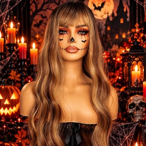 May include: A long, wavy, light brown wig with bangs, displayed on a mannequin head. The mannequin features detailed Halloween-themed face paint, including a black nose, bat shapes under the eyes, and stitched lines extending from the corners of the mouth.