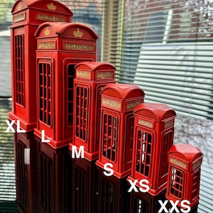 May include: Five red miniature replica telephone boxes in various sizes, labelled XL, L, M, S, and XS. The boxes are made of metal and have a classic British design.