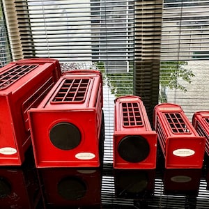 May include: A set of six red miniature telephone boxes, decreasing in size from left to right. The boxes are made of metal and have a classic British design.