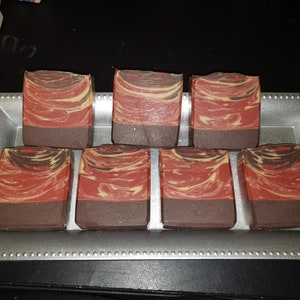 May include: Seven bars of handmade soap in a silver tray. The soap is red, brown, and cream colored with a marbled swirl pattern.