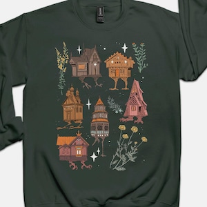 May include: A dark green sweatshirt with a whimsical illustration of houses with legs and flowers. The houses are in various styles and colors, including brown, pink, and blue. The flowers are white and yellow.
