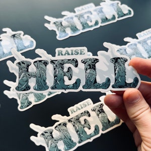 May include: A set of five white stickers with the words "Raise Hell" printed in black. The letters are stylized and filled with a black and white graphic design.