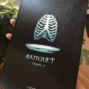 May include: A black book cover with a teal ribcage illustration and a plate underneath. The text "BANQUET" and "Chapter 2." is printed in white. The author's name, "A. SZABLA", is printed in white at the bottom.