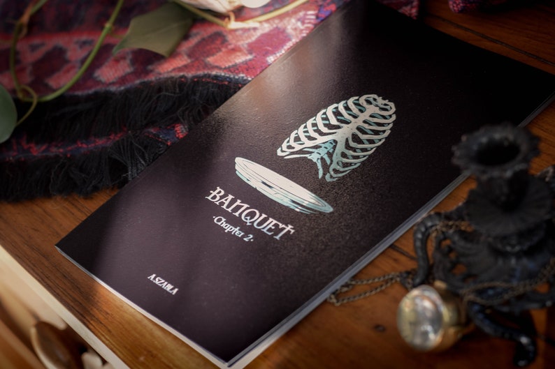 May include: A black book with the title "Banquet" and the subtitle "Chapter 2." The cover features a stylized illustration of a ribcage and a plate.