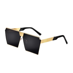 May include: Black square sunglasses with a gold metal frame. The sunglasses have a geometric shape and a black lens.