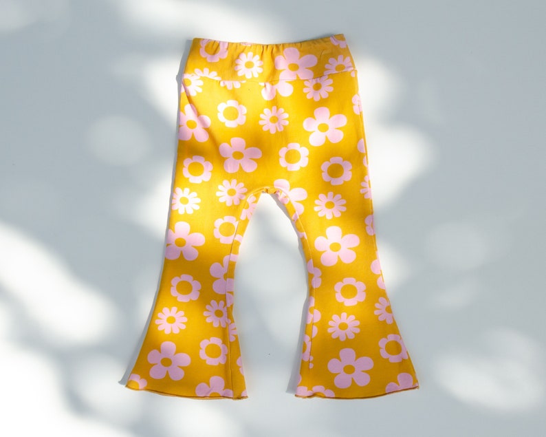 May include: Yellow bell bottom pants with a pink floral pattern.