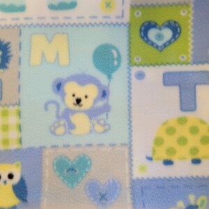 May include: A blue and white patchwork fabric with various animal and letter designs. The fabric features a monkey holding a balloon, a turtle, an owl, a lion, and the letters H, M, and T.