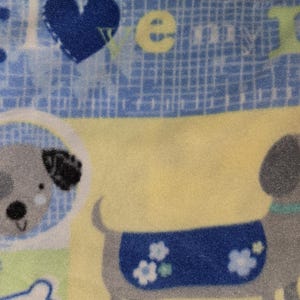 May include: A light blue and yellow patterned fabric featuring cartoon dogs and the words "I love my dog". The fabric has a grid-like pattern and includes images of dog faces and a dachshund.