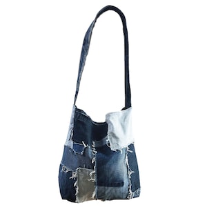 May include: A denim patchwork shoulder bag with a long strap. The bag is made from various shades of blue denim, with visible stitching and frayed edges. The bag is designed to be worn over the shoulder.