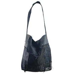 May include: A patchwork denim shoulder bag in various shades of blue and gray. The bag features a long strap and is constructed from irregularly shaped denim pieces, giving it a unique, handcrafted appearance. The bag has a casual, relaxed style.