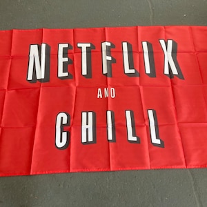 May include: Red fabric flag with white text that reads "NETFLIX AND CHILL".