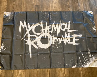 May include: Black and white flag with the words "My Chemical Romance" written in a stylized font. The background is black with white paint splatters.