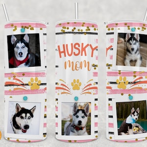 May include: A white tumbler with a pink and black striped design. The tumbler has a gold glitter accent and features photos of Siberian Huskies. The text "Husky Mom" is printed on the tumbler.