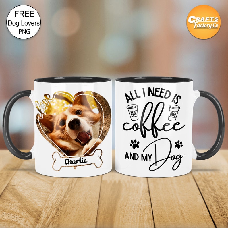 May include: White ceramic coffee mug with black rim and handle. The mug has a black paw print design and the text "All I need is coffee and my dog". The mug is next to a white ceramic mug with a black rim and handle. The mug has a heart-shaped photo of a dog with the text "love Charlie" below the photo.