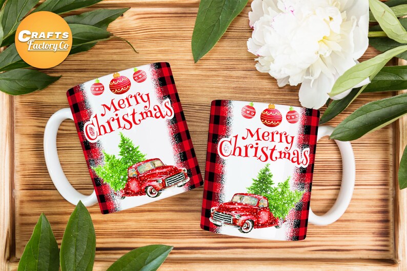 May include: Two white ceramic mugs with red and black checked designs. The mugs feature a red truck carrying a Christmas tree and the text "Merry Christmas".