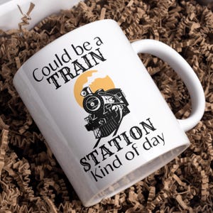 May include: White ceramic mug with a black and white illustration of a train engine with the text "Could be a TRAIN STATION kind of day".