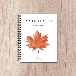 May include: A spiral bound notebook with a white cover featuring the text "Maple Sugaring: A Unit Study" and a watercolour illustration of a red maple leaf. The bottom of the cover has the text "Raising Up Maples".