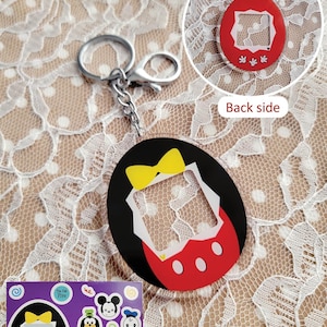 May include: A black, red, and yellow Mickey Mouse-themed keychain with a silver keyring and chain. The keychain has a cut-out design and includes a 4x6 sticker sheet with character stickers. The back side of the keychain is red.
