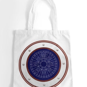 May include: White canvas tote bag with a navy blue and white compass design inside a brown circle with silver accents.