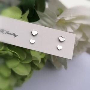 May include: A set of three silver heart-shaped stud earrings on a white card with the text "B Jewellery".