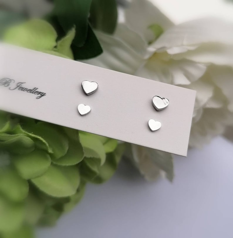 May include: A set of three silver heart-shaped stud earrings on a white card with the text "B Jewellery".