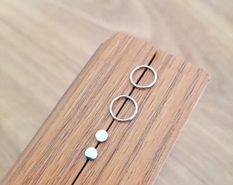 May include: A wooden box with two silver hoop earrings and two silver stud earrings.
