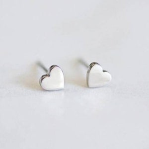 May include: A pair of silver heart-shaped stud earrings.