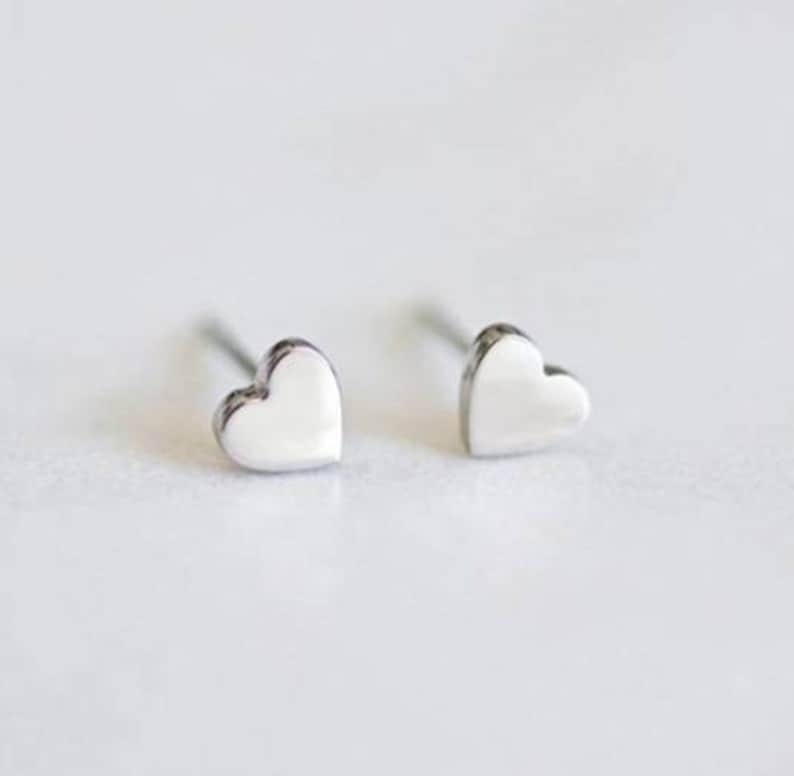 May include: A pair of silver heart-shaped stud earrings.