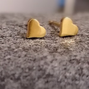 May include: A pair of gold heart-shaped stud earrings.