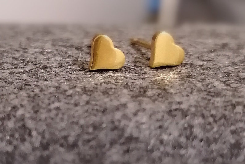 May include: A pair of gold heart-shaped stud earrings.