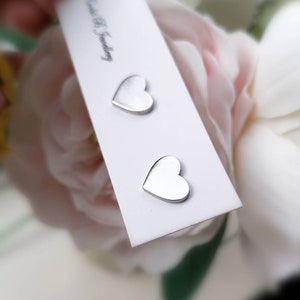 May include: Two silver heart-shaped stud earrings on a white card with the text "Bead & S Jewelry".