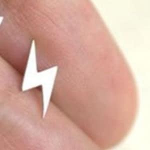 May include: A pair of silver lightning bolt stud earrings. The earrings are small and delicate, and they would make a great gift for a friend or loved one.