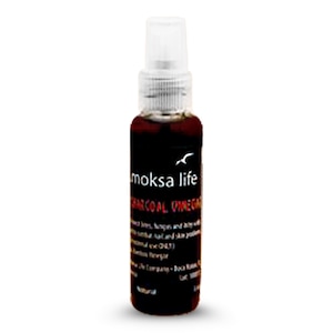 May include: A clear glass bottle with a black label that says "moksa life charcoal vinegar". The bottle has a black spray nozzle and is filled with a dark liquid.