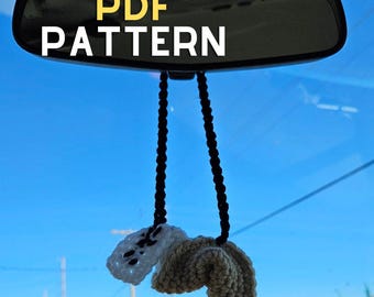May include: A rearview mirror with the text "PDF PATTERN" hanging from it. A white and beige crocheted car charm hangs from the mirror.