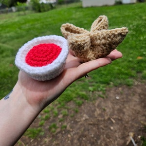 May include: Two crocheted amigurumi toys. One is a red and white mushroom, the other is a brown star.