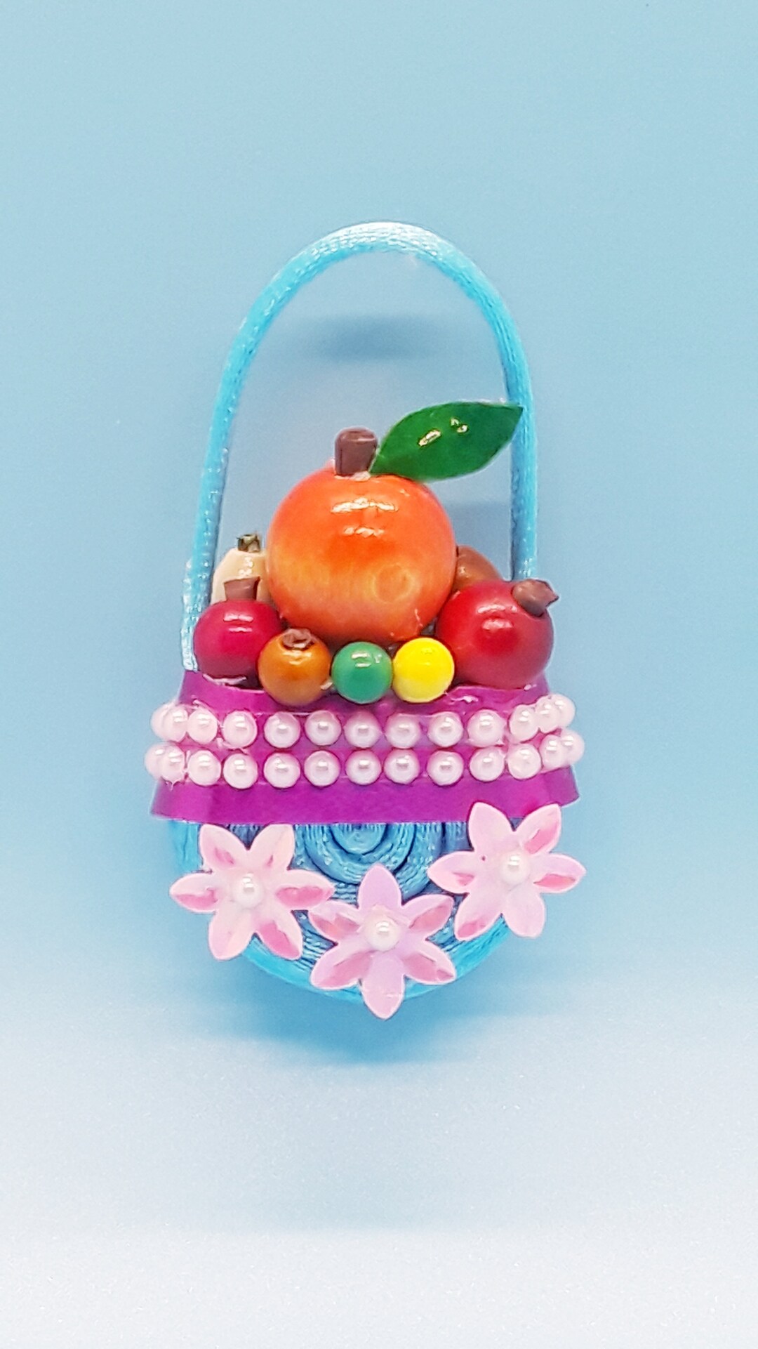 Light Blue Fruit Basket With a Purple Ribbon and Three Pink