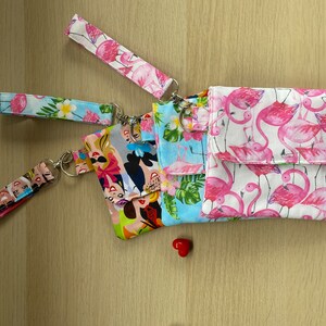 Può includere: Quattro piccole pochette in tessuto con motivi diversi. Le pochette hanno una chiusura a zip e un anello metallico per attaccare un portachiavi. I motivi includono un design floreale tropicale, un design di fenicotteri rosa, un design di principesse Disney e un design astratto colorato.