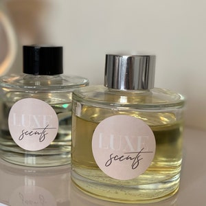 May include: Two clear glass bottles with gold lids and labels that say "LUXE scents". The bottles are filled with a light yellow liquid.